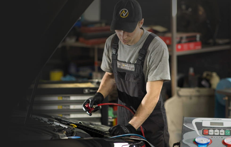 Kfz-Mechaniker wartet die Klimaanlage eines Autos in der Werkstatt